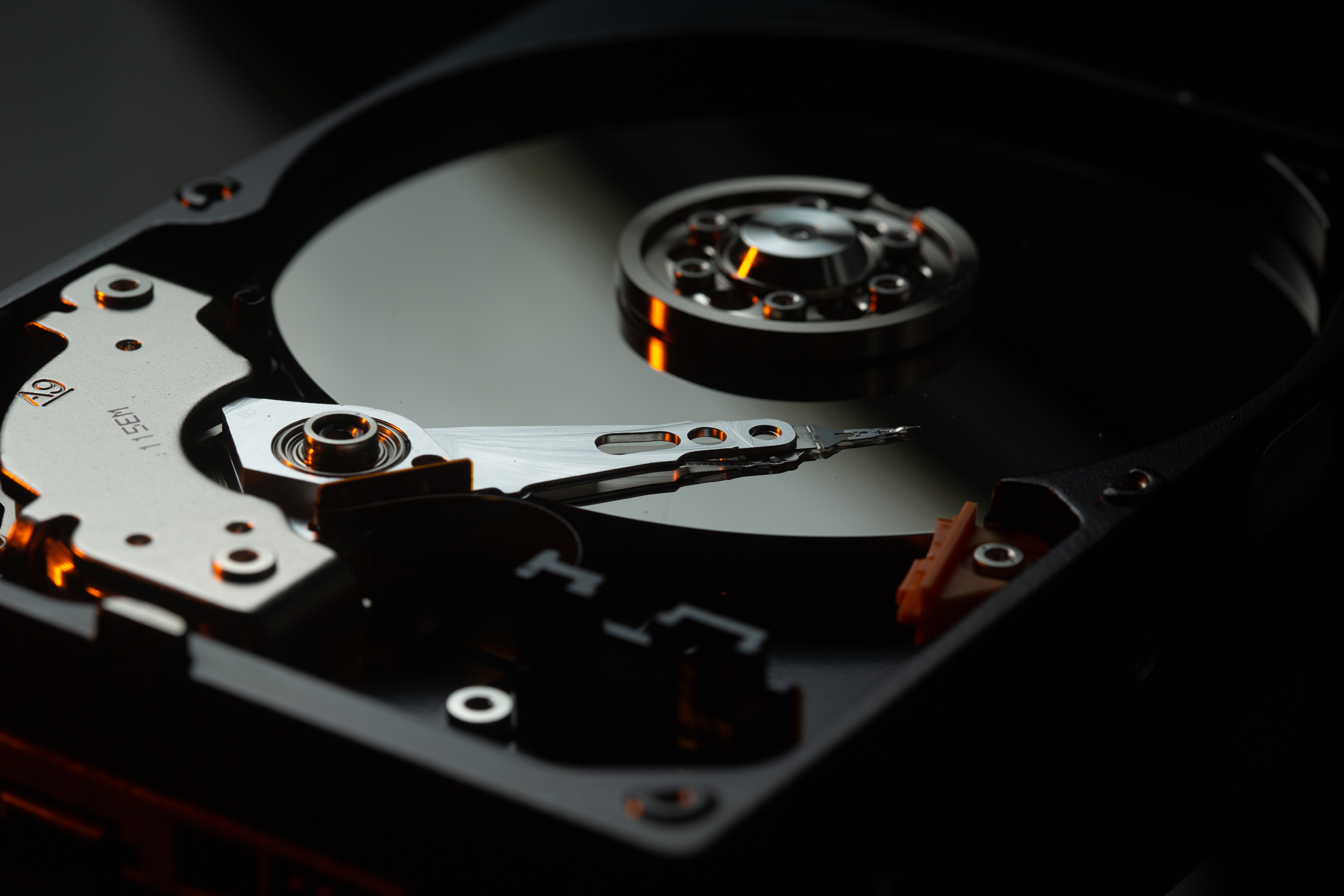An image of a bare hard drive platter with the head and disk exposed.
