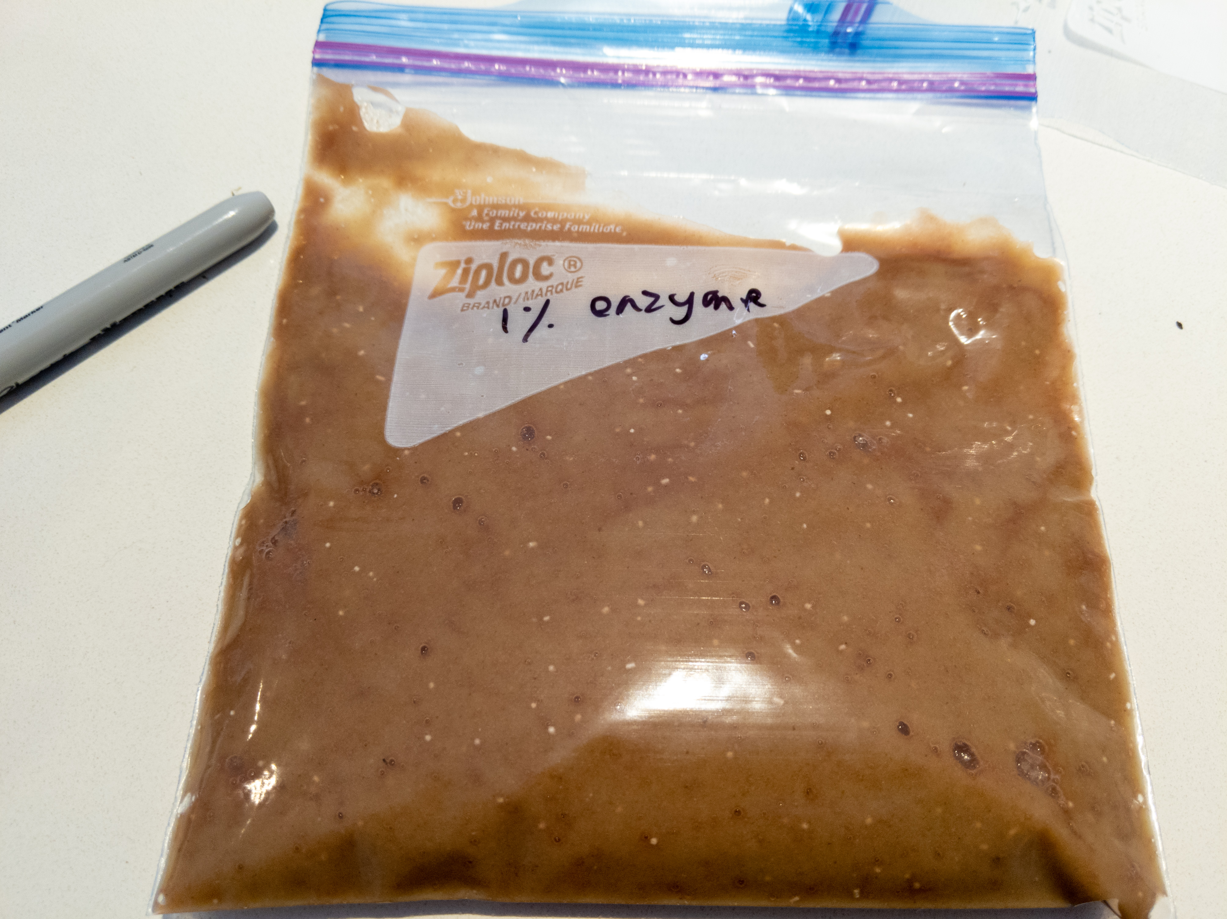 A picture of a ziplock bag filled with a brown puree. The bag is labelled '1% enzyme'