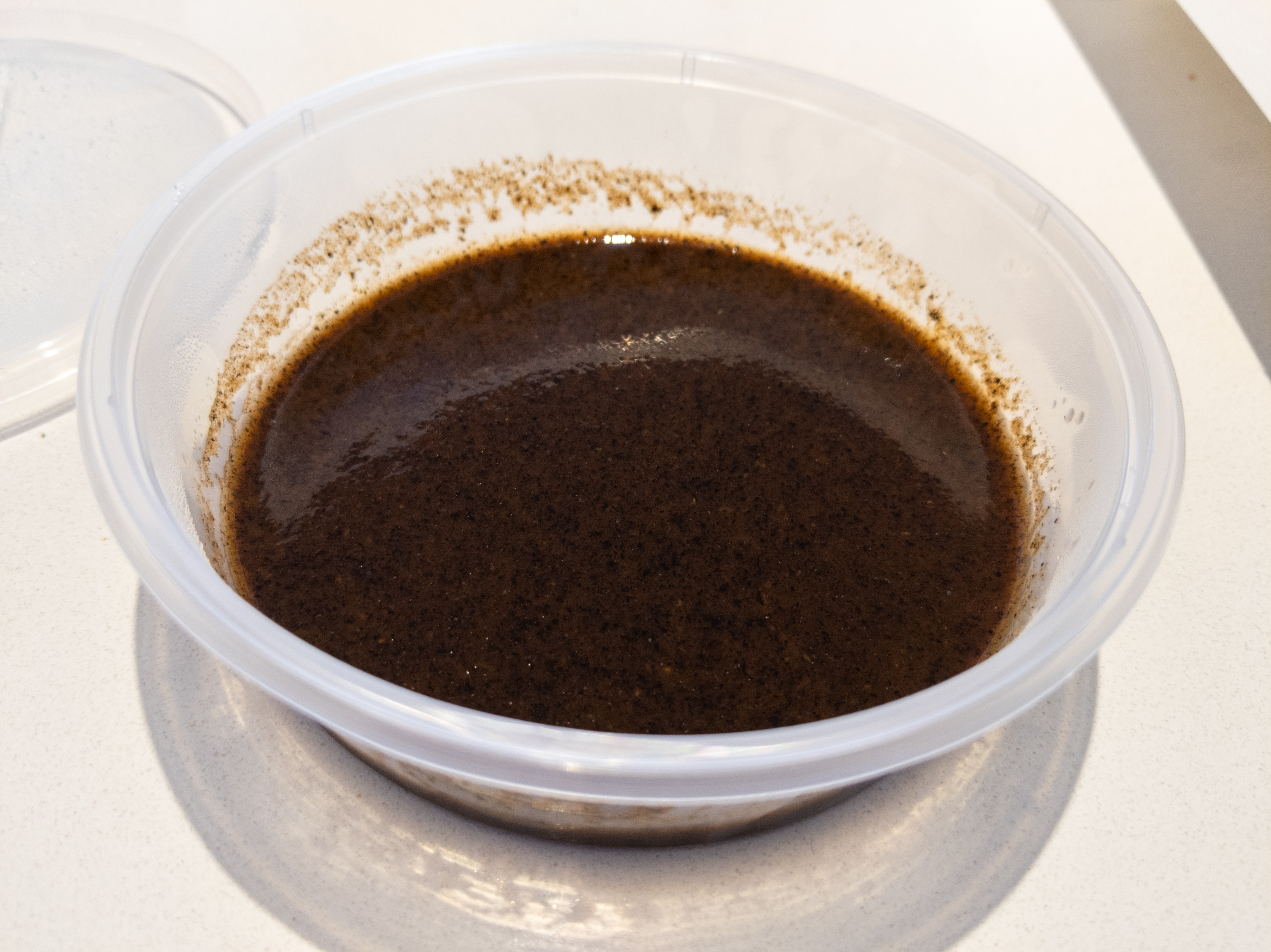 A small container filled with dark red, thick liquid, with black flecks throughout