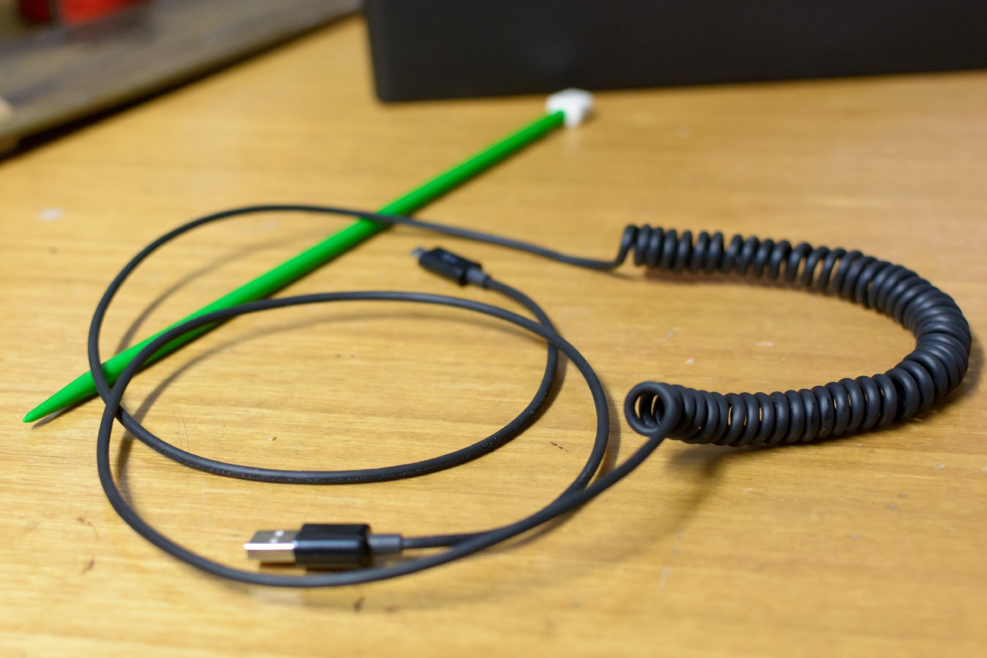 An image of an unevenly coiled cable resting on a wooden bench top.