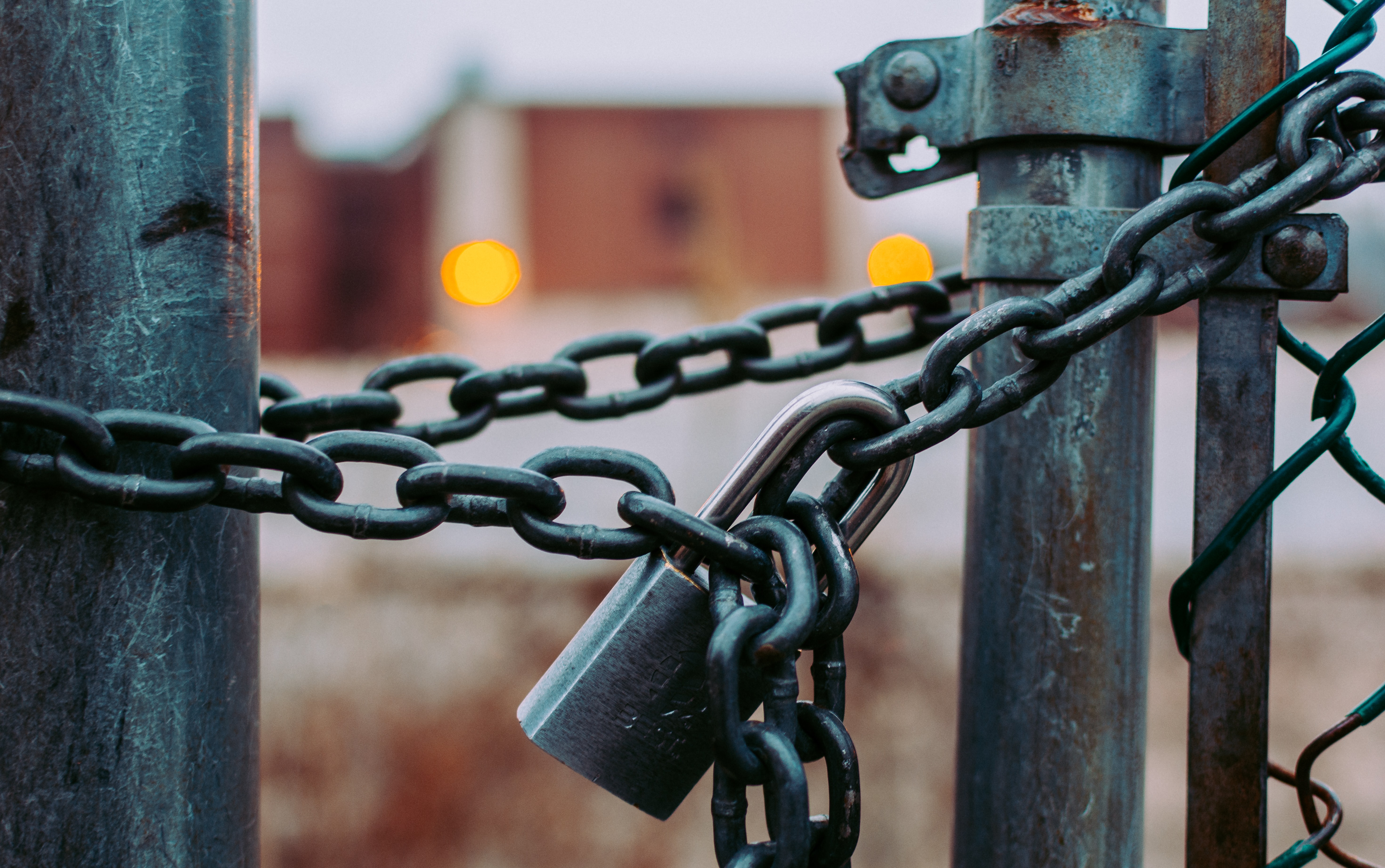 A close up of a gate that is locked closed by a padlock and some chain