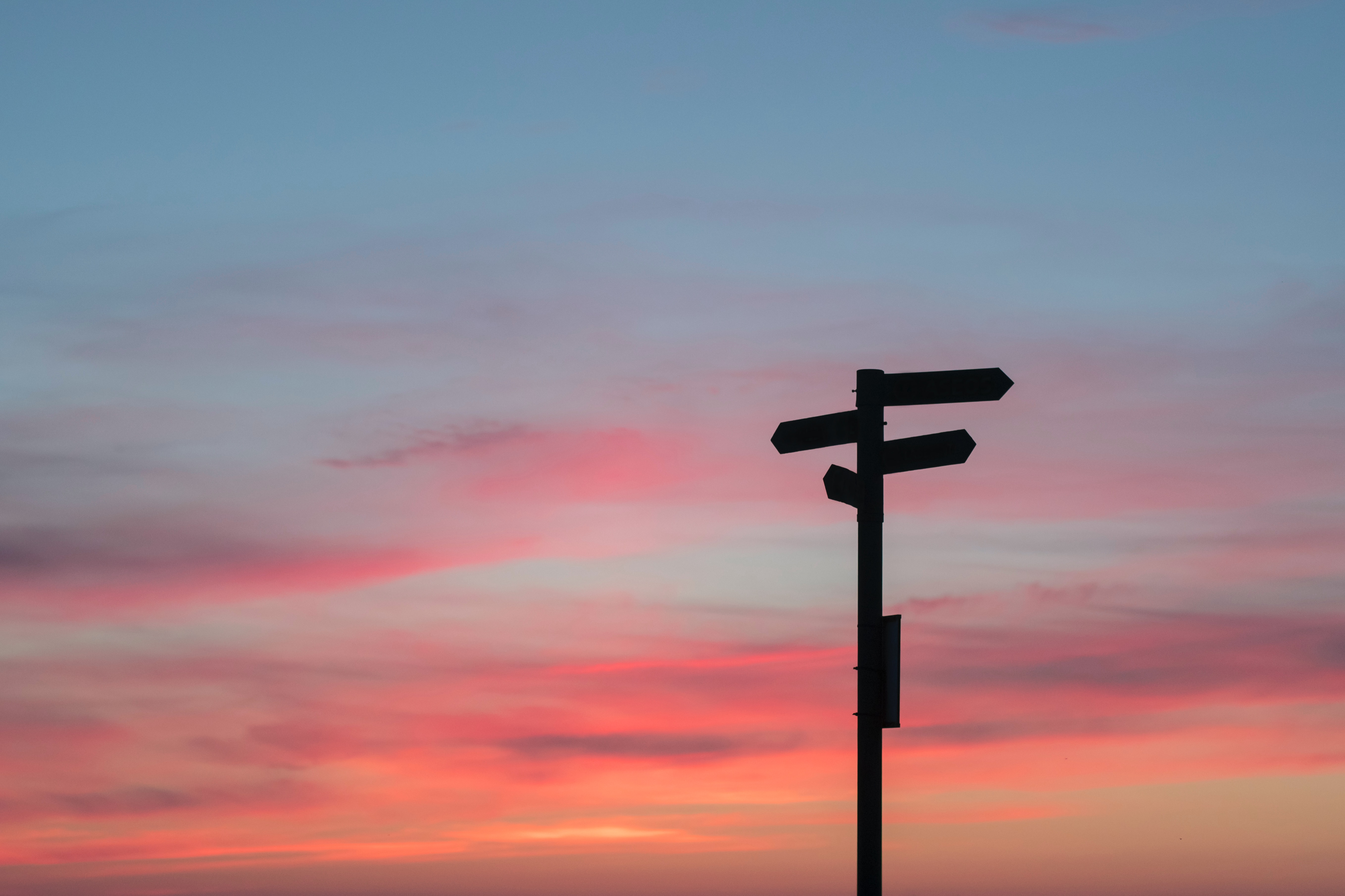 A photo of a sunset with the silhouette of a signpost